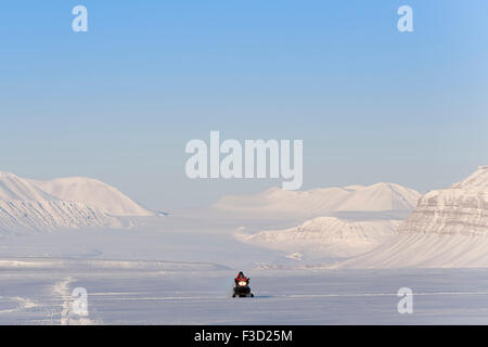 L'homme sur motoneige sur son chemin dans un paysage de neige avec Tunabreen Tempelfjorden, derrière le glacier, Spitsbergen, Svalbard, No Banque D'Images