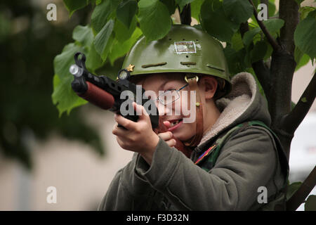 Un jeune garçon portant un casque de l'armée US vise avec le pistolet jouet pendant la reconstitution de l'insurrection de Prague 1945 à Prague, en République tchèque, le 9 mai 2015. Banque D'Images