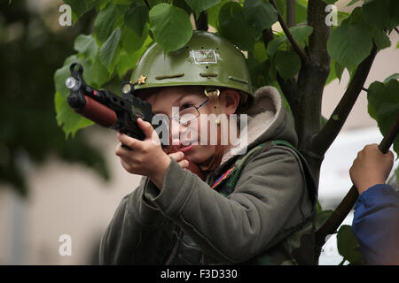 Un jeune garçon portant un casque de l'armée US vise avec le pistolet jouet pendant la reconstitution de l'insurrection de Prague 1945 à Prague, en République tchèque, le 9 mai 2015. Banque D'Images