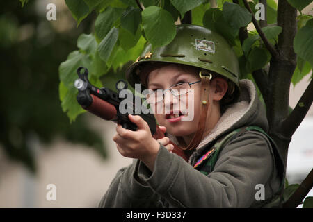 Un jeune garçon portant un casque de l'armée US vise avec le pistolet jouet pendant la reconstitution de l'insurrection de Prague 1945 à Prague, en République tchèque, le 9 mai 2015. Banque D'Images