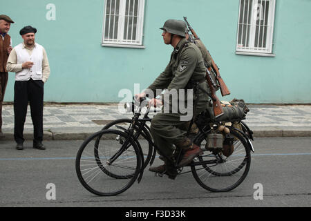 Comme en uniforme nazi allemand reconstitueurs soldats aller en vélo au cours de la reconstitution de l'insurrection de Prague 1945 à Prague, en République tchèque, le 9 mai 2015. Banque D'Images