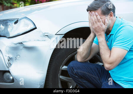 L'inspection des dommages après le pilote malheureux accident de voiture Banque D'Images