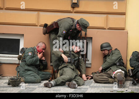 En tant que soldats en uniforme reconstitueurs de l'Armée de libération russe (OAK) faire semblant d'être blessés au cours de la reconstitution de l'insurrection de Prague 1945 à Prague, en République tchèque, le 9 mai 2015. L'Armée de libération russe également connu sous le nom de l'Armée de Vlasov est venu à l'aide de la République Tchèque Prague pour soutenir les insurgés soulèvement contre l'occupation allemande qui a débuté le 5 mai 1945. Banque D'Images