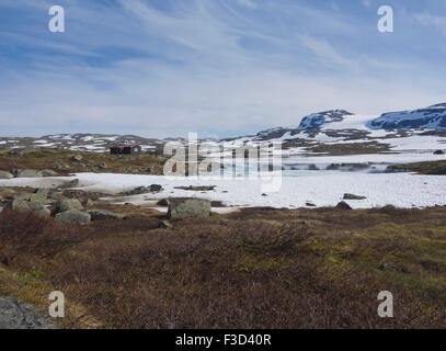 Vue panoramique montagnes norvégiennes, dans la petite cabine, lac, plaques de neige et glacier lointain, Finse, la Norvège Hardangervidda Banque D'Images