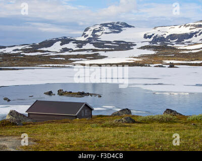 Vue panoramique montagnes norvégiennes, dans la petite cabine, lac, plaques de neige et glacier lointain, Finse, la Norvège Hardangervidda Banque D'Images