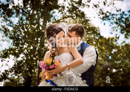 Heureuse mariée, marié debout dans Green Park, sourire, rire. Des amoureux au jour du mariage. Banque D'Images