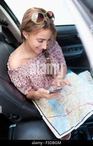 Woman téléphone en voiture avec la carte au tour Banque D'Images