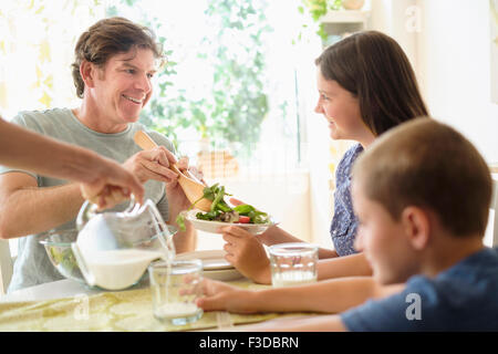 Enfants (8-9, 10-11) eating salad avec les parents Banque D'Images