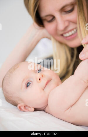 Mère jouant avec baby girl (2-5 mois) on bed Banque D'Images