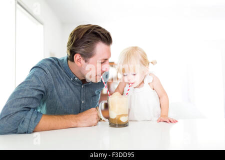Milkshake potable père avec sa fille (2-3) Banque D'Images