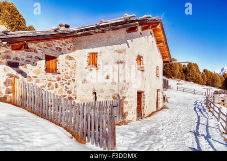 Chalet alpin entouré par une clôture dans la neige entre les sommets enneigés et les forêts de pins sur une journée ensoleillée en hiver Banque D'Images