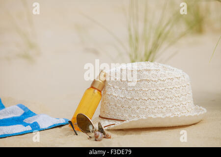 Set de plage summer hat sunglasses et lotion pour la peau allongé sur le sable.. Tout ce dont vous avez besoin pour se reposer et se détendre Banque D'Images
