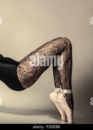 Belle femme danseuse de ballet, partie de corps jambes dans les chaussures et les collants dentelle noir sur fond gris, studio shot Banque D'Images