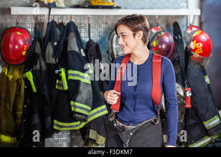 Debout contre des uniformes à pompier fire station Banque D'Images