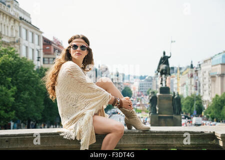 Femme aux cheveux longs en tourisme vêtements chic boho détente sur parapet dans le centre historique de Prague. Dans l'arrière-plan Saint Nous Banque D'Images