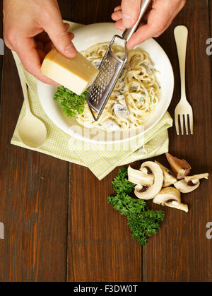 Râper le fromage parmesan chef sur les pâtes à la carbonara, vue du dessus Banque D'Images