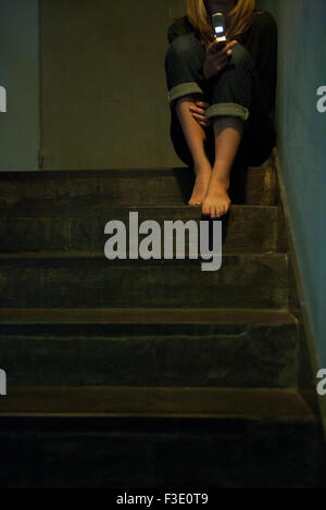 Femme assise seule dans la messagerie texte d'escalier Banque D'Images