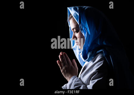 Vierge Marie avec voile bleu priant sur fond noir Banque D'Images