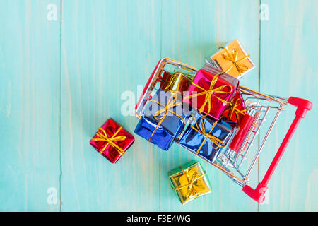 Panier plein de cadeaux colorés bleu sur fond de bois Banque D'Images