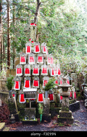 Le Japon, Koyasan, cimetière Okunoin. Une pyramide constituée de petits rouges superposés bibbed statues Jizo, avec une plus grande sur le dessus de la forêt de cèdres. Banque D'Images