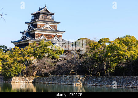 Château d'Hiroshima. Borogata reconstruit avec des arbres autour de type garder. Premier plan le fossé et Honmaru Ishigaki mur de pierre Banque D'Images