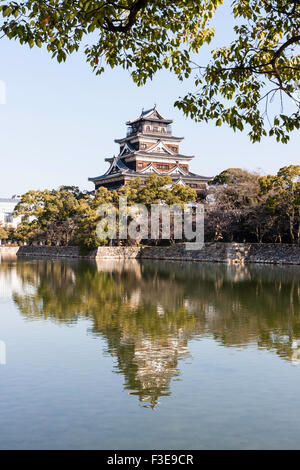 Château d'Hiroshima. Borogata reconstruit avec des arbres autour de type garder. Premier plan le fossé et Honmaru Ishigaki mur de pierre. Tenir compte dans ses douves. Banque D'Images