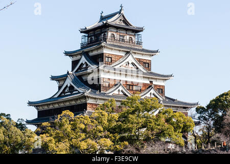 Château d'Hiroshima. Borogata reconstruit avec des arbres autour de type garder. Bois brun et blanc design en plâtre, vu contre ciel bleu clair. Banque D'Images