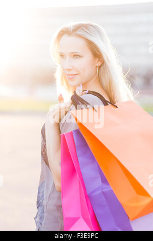 Jeune femme se tient avec les sacs contre le soleil. Belle fille adultes à l'extérieur après le magasinage Banque D'Images