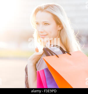 Jeune femme se tient avec les sacs contre le soleil. Belle fille adultes à l'extérieur après le magasinage Banque D'Images