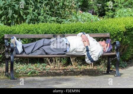 Un homme dort sur un banc de parc, UK Banque D'Images