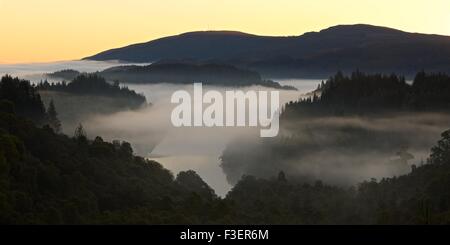 La brume s'attarde au-dessus du Loch Achray sur un froid matin d'automne prises à partir du col de Dukes Banque D'Images