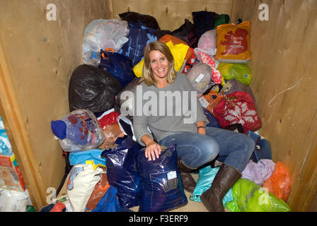 Bénévole dans un entrepôt de l'entreprise dépose posant pour une photo dans des sacs de dons de vêtements etc pour les réfugiés syriens Banque D'Images