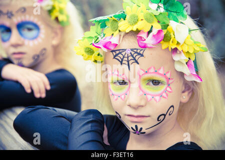 Peu de filles avec des vêtements noirs et maquillage crâne en sucre à la caméra au sérieux Banque D'Images