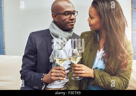 Loving couple dans une étreinte étroite toasting each other with white wine comme ils regarder profondément dans les yeux de chacun Banque D'Images