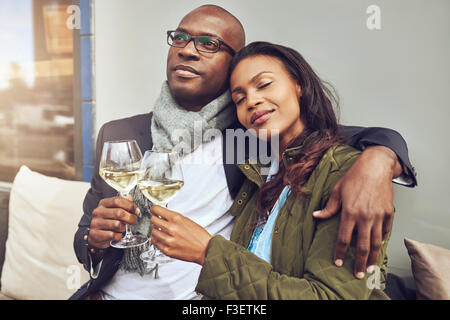 Blissful young couple relaxing in chaque bras tout en prenant un verre de vin blanc dans un restaurant table Banque D'Images