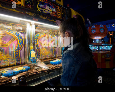 Une jeune fille joue une machine à sous dans un penny de jeux électroniques. Banque D'Images