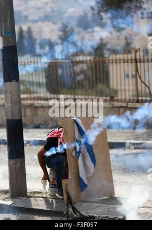 Un manifestant palestinien tenant un drapeau israélien se met à couvert que gaz lacrymogènes est tué par des soldats israéliens (pas vu) lors d'une manifestation dans la ville cisjordanienne de Bethléem. À la suite des funérailles de jeune Palestinien de 13 ans d'Abed al-Rahman Obeidallah qui a été tué par un soldat israélien dans le camp de réfugiés de Aida dans la ville cisjordanienne de Bethléem, des centaines de jeunes Palestiniens se sont affrontés violemment avec des soldats israéliens à Bethléem. Les jeunes Palestiniens sont descendus dans les rues de Bethléem, le camp de réfugiés de Aida de marche vers la poste de contrôle militaire israélien dans le nord de Bethléem. Des soldats israéliens ch Banque D'Images