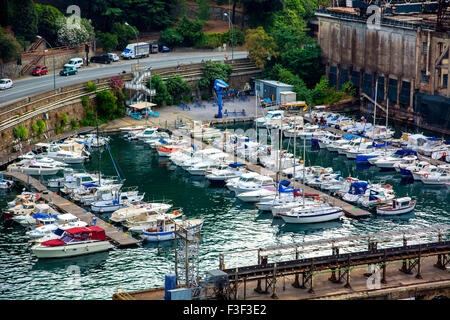 Sommaire des voiliers et yachts ancrés dans petite marina et entouré de bâtiments industriels et niché à côté de la route courbe Banque D'Images