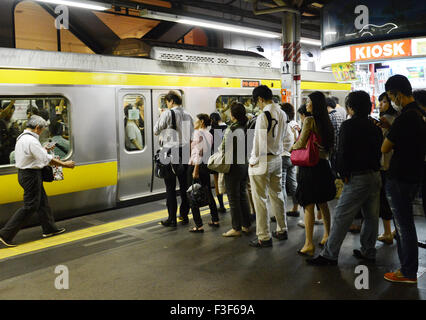 Une plate-forme occupée au cours de la soirée, aux heures de pointe dans la gare de Shinjuku, Tokyo. Banque D'Images