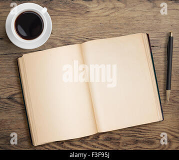 Livre ouvert avec plume et tasse à café sur table en bois ancien Banque D'Images