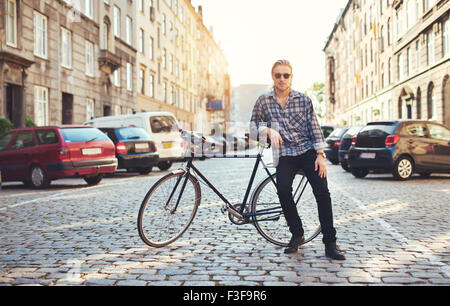 La vie dans la ville, portrait de jeune homme assis sur son vélo Banque D'Images
