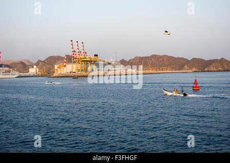 Bateau de croisière, le yacht du Sultan et un bateau de pêche dans le port de Mascate au Sultanat d'Oman, avec des montagnes dans le backg Banque D'Images