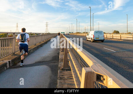 L'homme en marche ou le jogging le long d'une route avec trafic tôt le matin, Nottingham, England, UK Banque D'Images