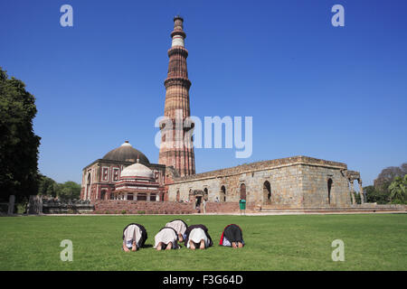 Enfants faire Namaz Alai Darwaza Imam Zamin tombeau et Qutab Minar tour de grès rouge de l'art musulman Indo Delhi Banque D'Images