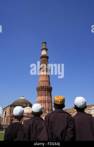 Les enfants faisant la prière religieuse Namaz Qutab Minar tour de grès rouge ; l'art musulman ; Delhi Indo Banque D'Images