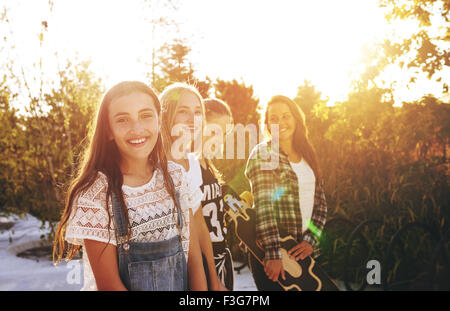 Teenage girl looking at camera avec des amis dans l'arrière-plan Banque D'Images