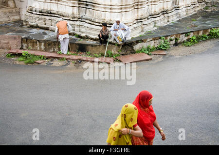 Deux femmes rurales indiennes en passant sur la route près d'un ancien village Delwara Jain temple ; ; ; ; Inde Rajasthan Udaipur Banque D'Images