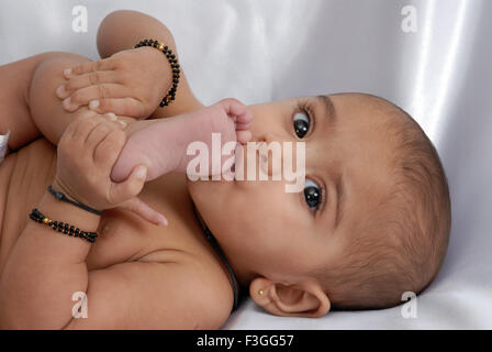 Indian child baby lying on back toe sucking sur fond blanc - M.# 152 Banque D'Images