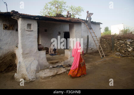 Maison ancienne dans village femme en robe rose marche ; Village ; Dilwara Udaipur Rajasthan ; Inde ; Banque D'Images