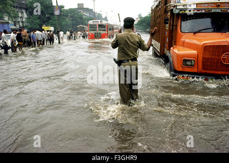 Une police de la circulation dans l'eau jusqu'aux genoux le contrôle de la circulation sur des routes inondées ; Bombay Mumbai Maharashtra ; Inde ; Banque D'Images